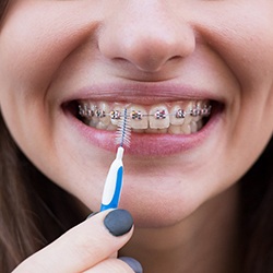 Woman smiling while using an interproximal toothbrush